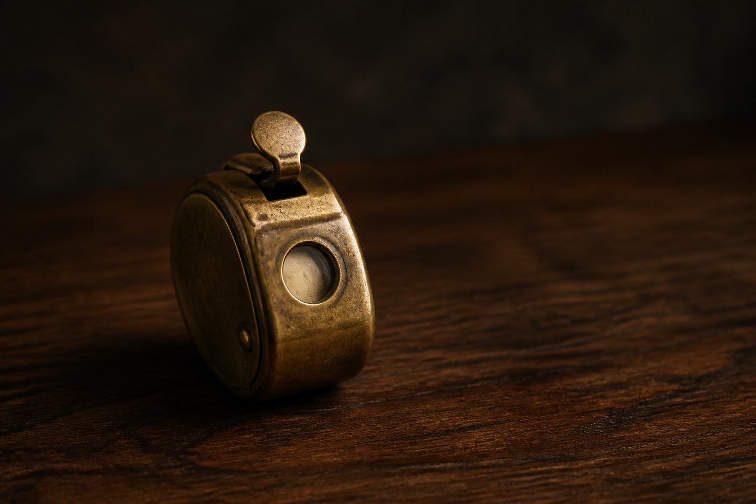 A brass mechanical tally counter resting on a dark walnut desk under warm directional light