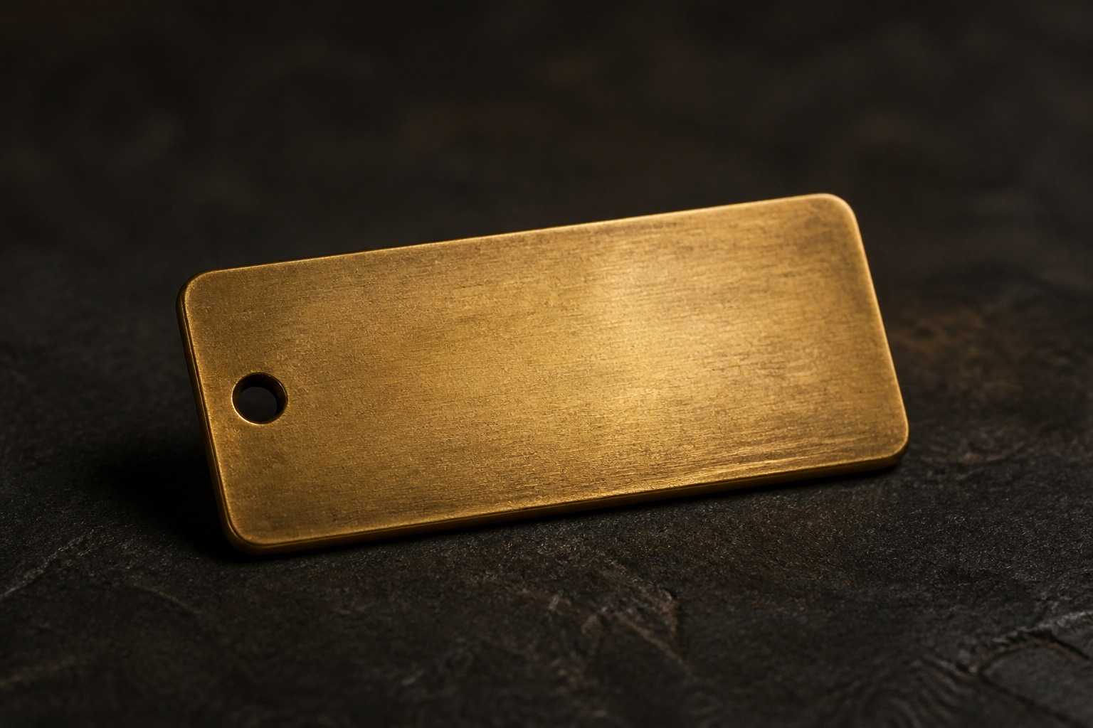 A substantial blank brass price tag resting under warm light on a dark stone surface
